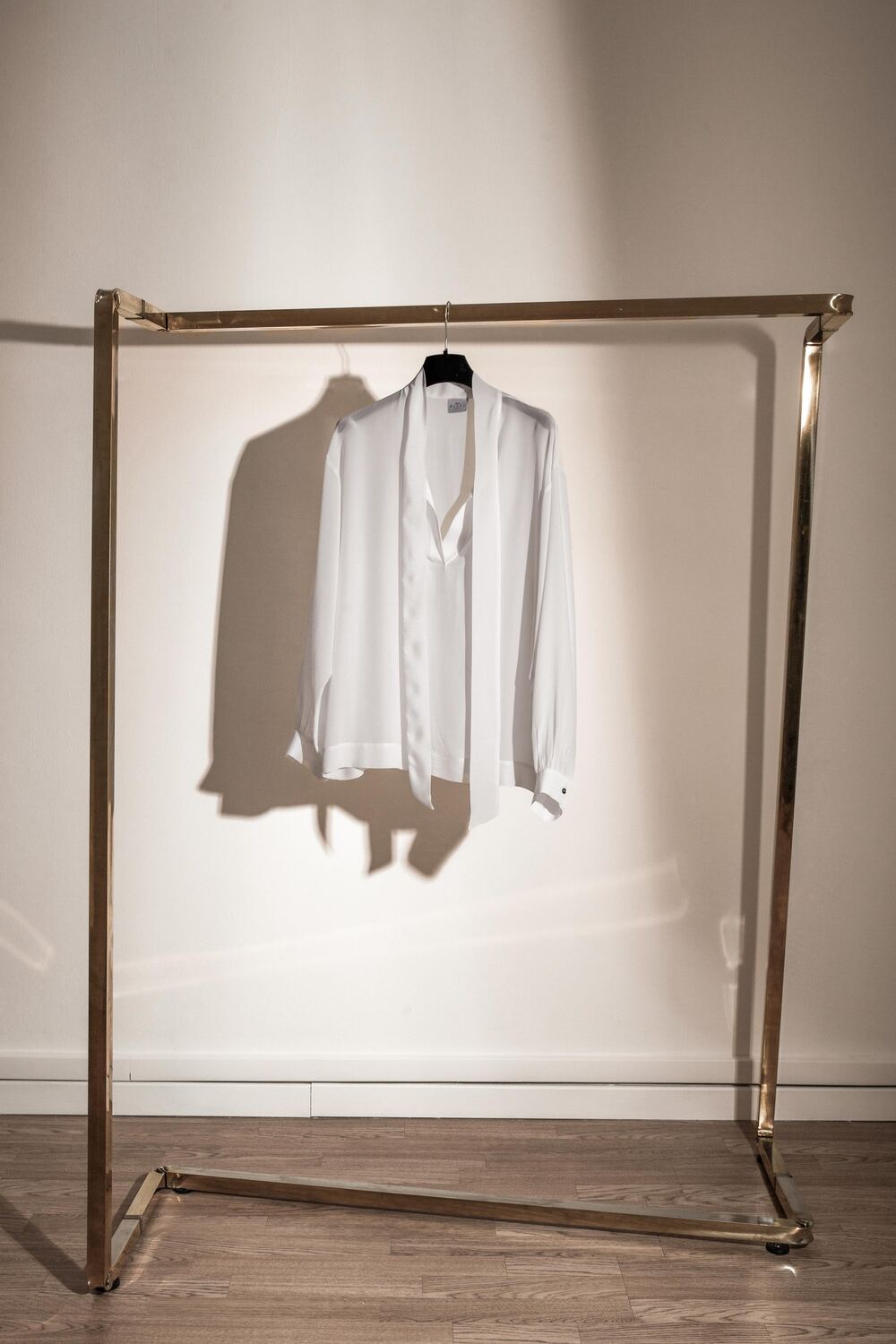 Una blusa di seta bianca appesa a uno stender dorato