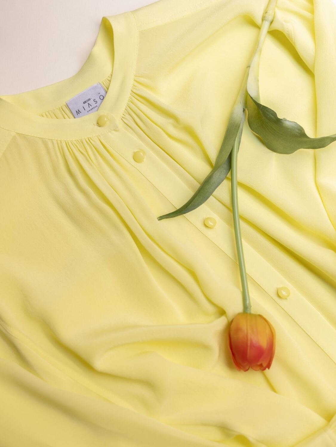 Una blusa di seta gialla con un tulipano appoggiato sopra